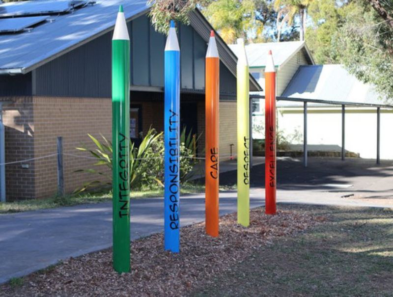 Big colour pencils in the field of a school